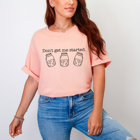 Person wearing a pink t-shirt with text and graphics, standing against a plain background