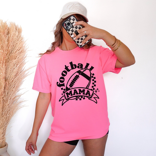 Person wearing a pink t-shirt with 'Football Mama' text, holding a phone with a checkered case.