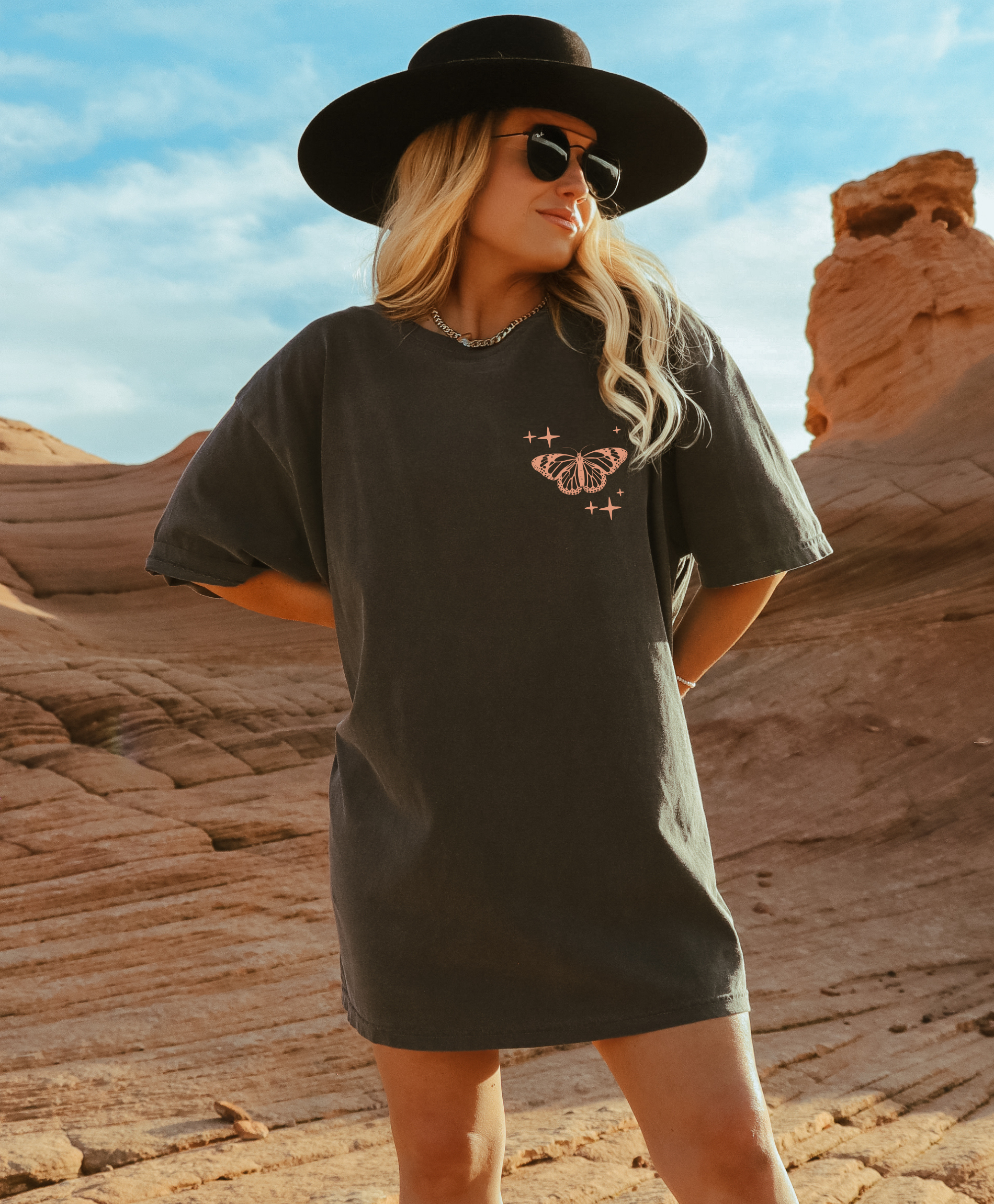 Woman wearing a grey t-shirt with a butterfly design in a desert setting