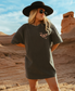 Woman wearing a grey t-shirt with a butterfly design in a desert setting