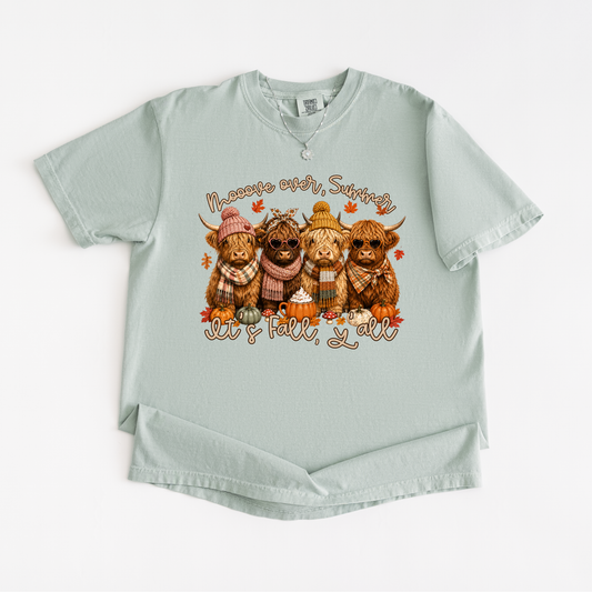 A light sage green short-sleeve t-shirt with a graphic of four Highlanders wearing autumn clothing and pumpkins, with the text 'Halloween over, Saturday' and 'Get 'tall, y'all' printed on the front.