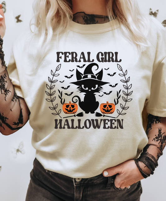 Person wearing a white t-shirt with 'Feral Girl Halloween' design featuring a black cat and pumpkins.